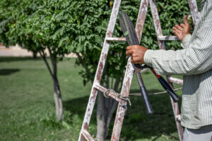 Gardener in the garden with a temporary hut and large shears for pruning bushes.